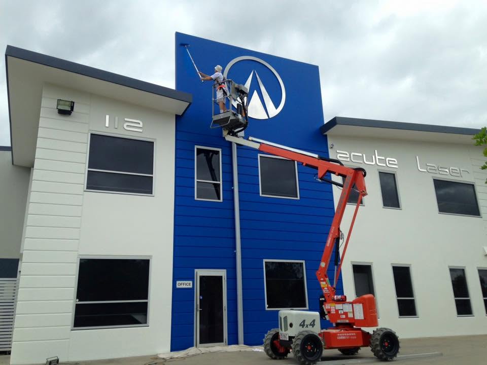 The Cool Roof crew painting a commercial facade from an EWP boom lift